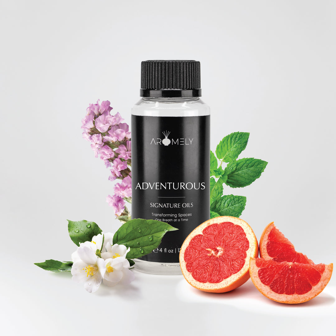 Adventurous 120ml Aromely diffuser oil in a sleek black bottle, surrounded by fresh mint leaves, jasmine flowers, purple blossoms, and juicy grapefruit slices. A bold and invigorating citrus scent for home or office aromatherapy.