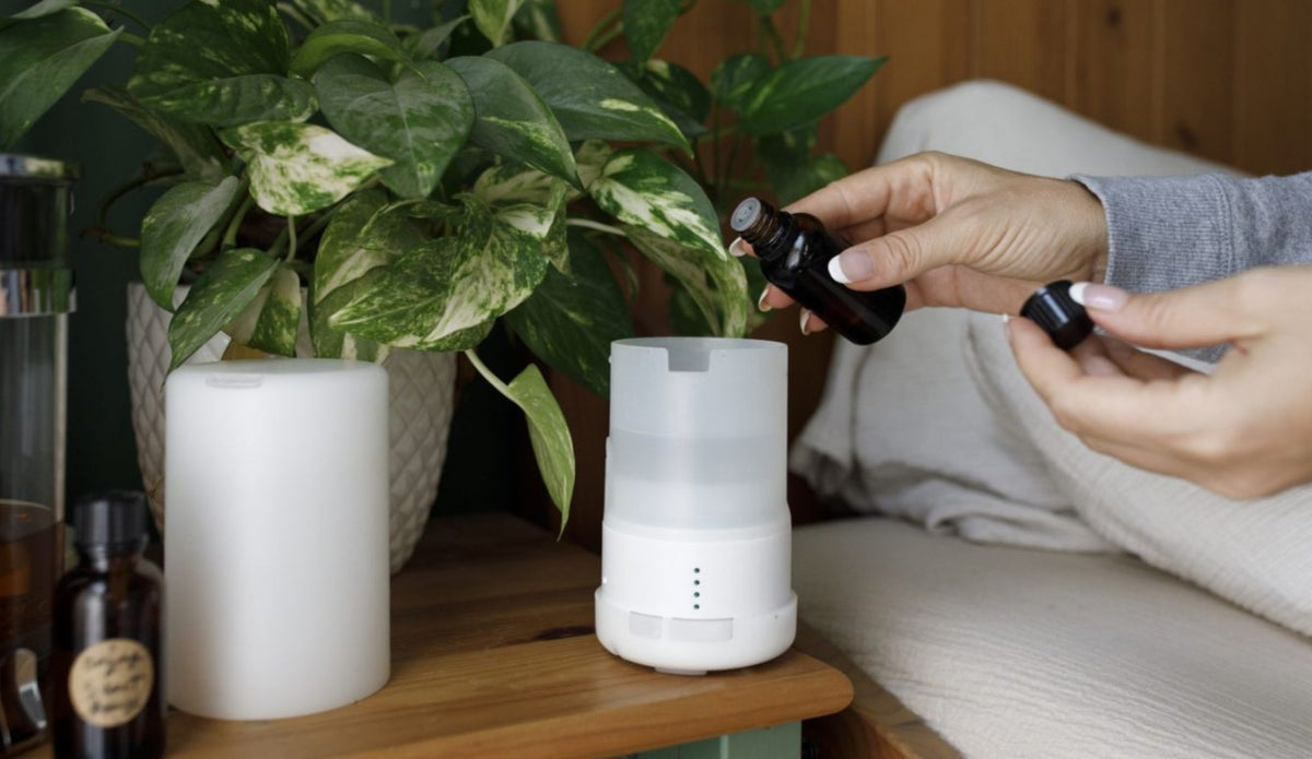Hand adding oil drops to a white diffuser