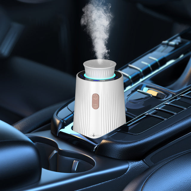 Compact car diffuser with steam emitting, placed in a vehicle cup holder, illuminated with a blue light ring.