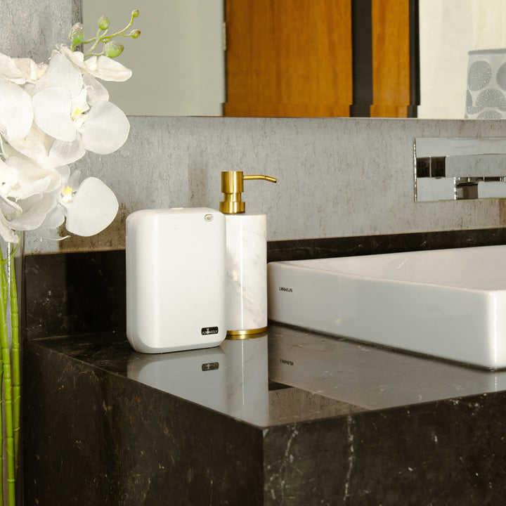 Aromely ARO-X25 Smart Aroma Diffuser placed on a modern bathroom counter next to a soap dispenser and white orchids.