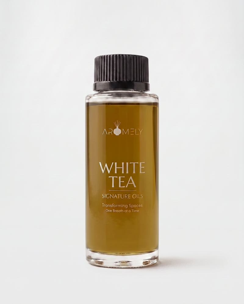 A clear glass bottle of Aromely White Tea Signature Oils containing amber-colored oil, topped with a black ribbed cap, set against a clean white background.