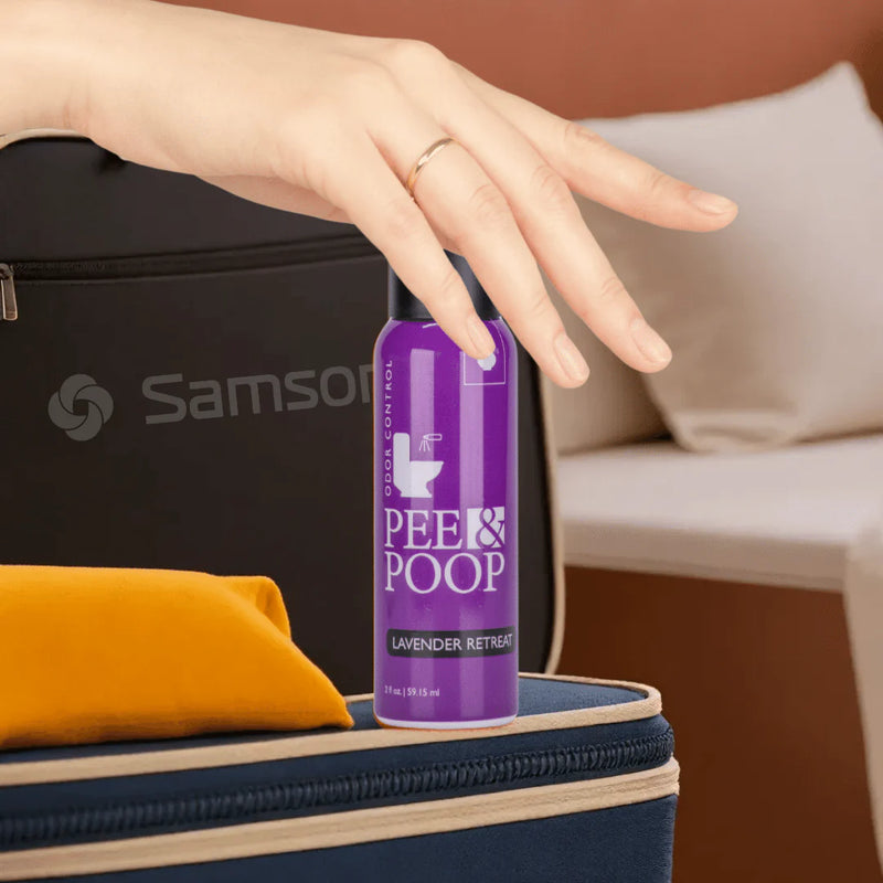 Hand packing Aromely Pee & Poop Lavender Retreat toilet spray into suitcase for travel use